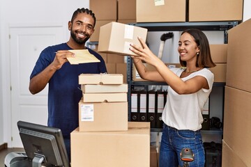 Man and woman business partners smiling confident holding packages at storehouse