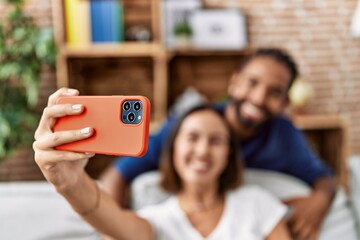 Man and woman couple smiling confident make selfie by the smartphone at home