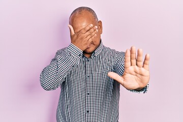 Middle age latin man wearing casual clothes covering eyes with hands and doing stop gesture with sad and fear expression. embarrassed and negative concept.