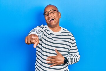 Middle age latin man wearing casual clothes and glasses laughing at you, pointing finger to the...