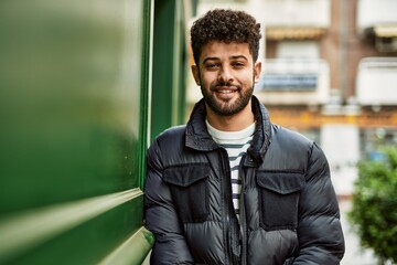 Young arab man smiling leaning on the wall