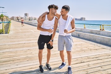 Two hispanic men sporty couple smiling confident and hugging each other standing at seaside