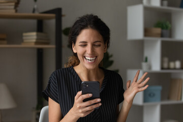 Overjoyed millennial hispanic woman reading amazing news in phone message overwhelmed with new...