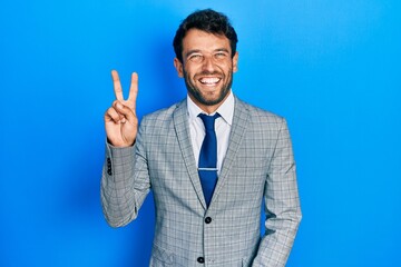 Handsome man with beard wearing business suit and tie smiling with happy face winking at the camera...