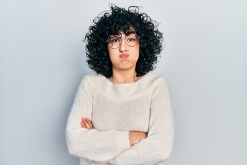 Young middle east woman with arms crossed gesture puffing cheeks with funny face. mouth inflated with air, catching air.