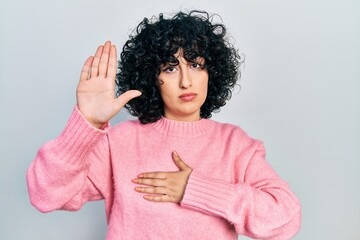 Young middle east woman wearing casual clothes swearing with hand on chest and open palm, making a...