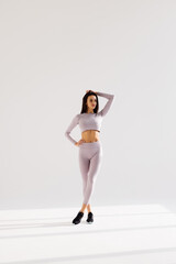 portrait of fitness woman in sport style standing against white background