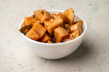 Korean marinated daikon radish in a white bowl on a light background.