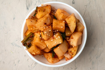 Korean marinated daikon radish in a white bowl on a light background. Top view.