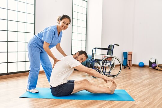 Middle age man and woman smiling confident having rehab session stretching at physiotherapy clinic