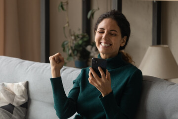 Good bit of luck. Excited cheering young hispanic woman raise fist up reading amazing job sales...