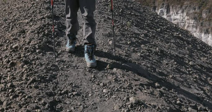 Feet walk on the frozen lava of an active volcano. Crown plan of legs walking on top of a mountain.