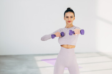 Fototapeta na wymiar Young Woman exercising with dumbbells at gym