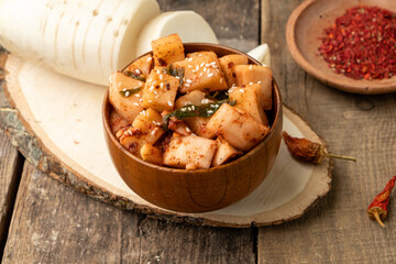 Classic Korean spicy salad of fermented daikon radish on a wooden table.