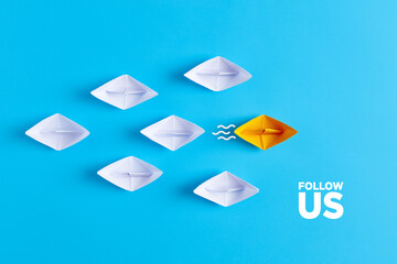 Yellow paper boat leads white paper ships with the follow us message. Social media or internet followers concept. - obrazy, fototapety, plakaty