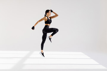Attractive excited fitness woman in sportwear jumping of joy isolated over white background