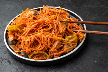 Korean salad with khe fish. Salad with pickled fish and carrots, close-up, dark background.