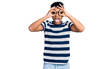 Fototapeta premium Young african american man wearing casual clothes and glasses doing ok gesture like binoculars sticking tongue out, eyes looking through fingers. crazy expression.