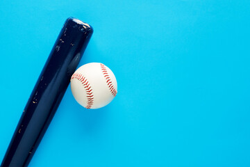 Wooden baseball bat and a baseball ball on blue background