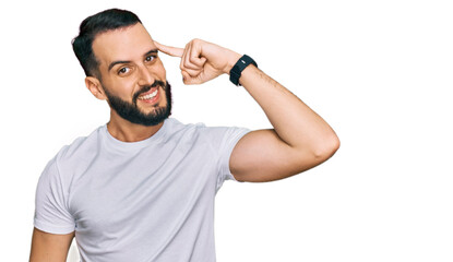 Naklejka premium Young man with beard wearing casual white t shirt smiling pointing to head with one finger, great idea or thought, good memory