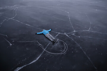 a man in ice skates lies on the transparent ice of the lake, view from above, aerial photography