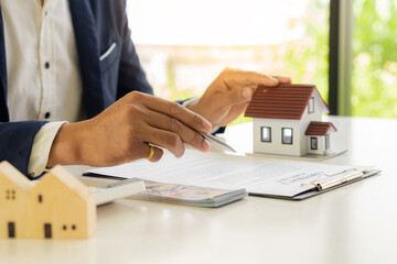 A real estate agent offers a sample home insurance home to sign the agreement. with documents of...