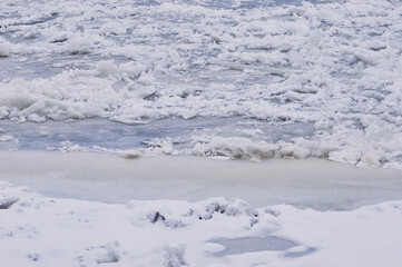 Obraz premium Snow-covered ice on the river during a snowfall. Winter texture.