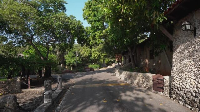Tour of the historic streets of the old city of artists. The seductive beauty of ancient architecture. A cozy street is surrounded by green tropical plants. Filmed at Altos de Chavon Republica Dominic