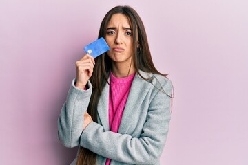 Young hispanic girl holding credit card depressed and worry for distress, crying angry and afraid. sad expression.