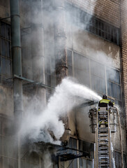 Firefighter on a lift extinguishes an abandoned building