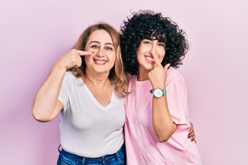 Fototapeta na wymiar Middle east mother and daughter wearing casual clothes pointing with hand finger to face and nose, smiling cheerful. beauty concept