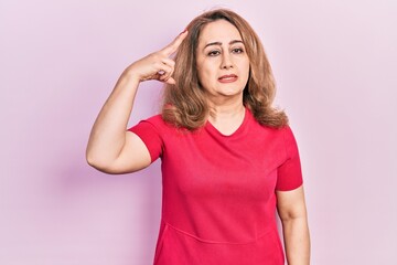 Fototapeta premium Middle age caucasian woman wearing casual clothes shooting and killing oneself pointing hand and fingers to head like gun, suicide gesture.