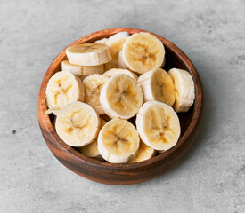 Photo of banana slices in a bowl on a concrete surface