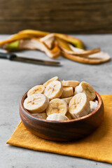 Photo of banana slices in a bowl on a concrete surface