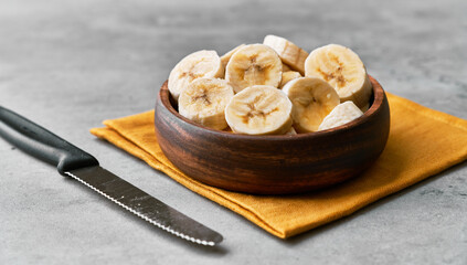 Photo of banana slices in a bowl on a concrete surface