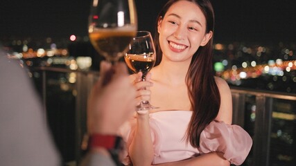 Young asian woman with sparklers is dancing and celebrating a new year. Fireworks, bengal lights in slow motion. Having fun at rooftop in the city.Happy interracial couple with glasses of wine .