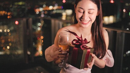 Young asian woman with sparklers is dancing and celebrating a new year. Fireworks, bengal lights in slow motion. Having fun at rooftop in the city.Happy interracial couple with glasses of wine .