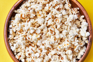  Bowl of salty popcorns on a yellow background