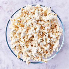 Bowl of salty popcorns on a marble surface