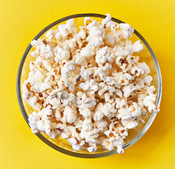  Bowl of salty popcorns on a yellow background