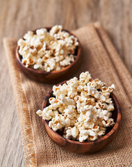  Bowls of salty popcorns on a wooden surface