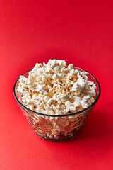  Bowl of salty popcorns on a red background