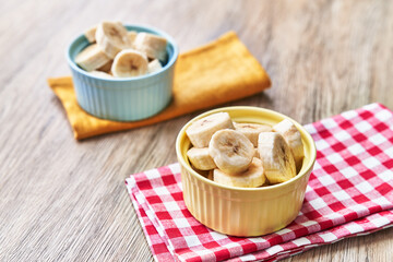  Bowls of slices of banana on a wooden table