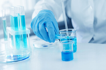 The scientist's hands are holding a flask and a laboratory pipette. A scientist is conducting research on a vaccine against coronavirus. Laboratory clinical trials.