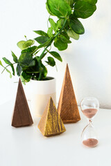.Wood triangles trees, eucalyptus branch and sand cllock on white background. Modern Christmas decoration..