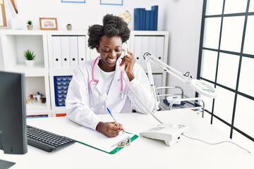 Young african american woman wearing doctor uniform talking on the telephone at clinic