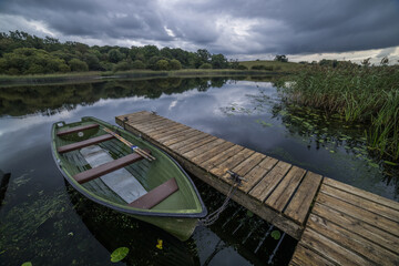 A rowing boat tied up at a wooden jetty at Crom Estate, Upper Lough Erne. County Fermanagh,...
