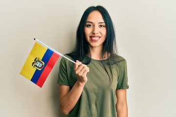 Young hispanic girl holding ecuador flag looking positive and happy standing and smiling with a...