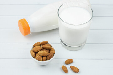 White ceramic bowl with almonds and a plastic bottle of almond milk. Alternative milk concept, food...