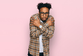 Young african american man with beard wearing casual clothes and glasses shaking and freezing for winter cold with sad and shock expression on face